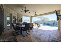 Stylish covered patio with an outdoor dining area, sitting area, and a view of the pool at 5621 N 189Th Dr, Litchfield Park, AZ 85340