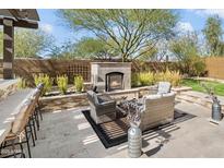 Outdoor fireplace with travertine patio, lounge seating, built-in bar, and desert landscaping at 22410 N 29Th Pl, Phoenix, AZ 85050