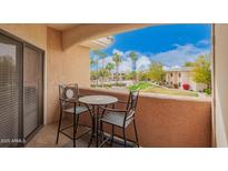 Cozy balcony seating area with a view of the community pool and palm trees at 10030 W Indian School Rd # 226, Phoenix, AZ 85037