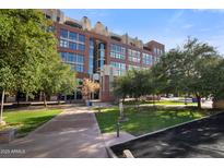 Multi-story brick building with manicured lawn, sidewalks, and mature shade trees on a clear day at 21 E 6Th St # 412, Tempe, AZ 85281