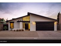 Charming single-story home features a modern design with a black garage door and desert landscaping at 5449 E Cambridge Ave, Phoenix, AZ 85008