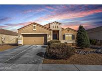 Inviting single-story home showcasing a two-car garage, desert landscaping, and picturesque sunset at 9450 W Georgia Ave, Glendale, AZ 85305