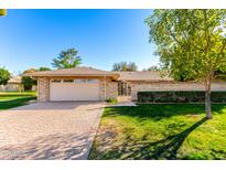 Charming single-story home with a brick facade, lush lawn, and a two-car garage at 10103 W Saddle Ridge Dr, Sun City, AZ 85373