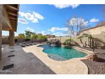 Large backyard with a luxurious pool, waterfall, basketball court, and covered patio at 14258 W Lisbon Ln, Surprise, AZ 85379