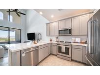 A modern kitchen featuring stainless steel appliances, gray cabinetry, and a breakfast bar overlooking the living area at 2511 W Queen Creek Rd # 479, Chandler, AZ 85248