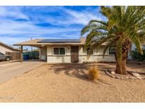 Charming single-story home with solar panels and desert landscaping, plus a large palm tree in the front yard at 280 W 23Rd Ave, Apache Junction, AZ 85120