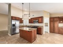 Spacious kitchen features wooden cabinets, granite countertops, a stainless steel refrigerator, and a center island at 3690 N 150Th Ave, Goodyear, AZ 85395