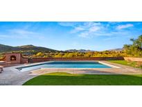Sparkling pool with a built-in brick fireplace and beautiful mountain backdrop at 5480 E Desert Creek Ln, Cave Creek, AZ 85331