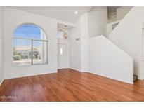 Bright living room with hardwood floors and large arched window providing ample natural light at 9264 E Hillery Way, Scottsdale, AZ 85260