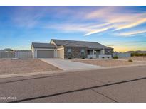 This house is clad with stone and has a three-car garage and desert landscaping at 12204 W Black Hawk Rd, Casa Grande, AZ 85194