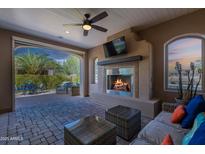 Comfortable covered patio with a fireplace and ceiling fan, perfect for relaxing and entertaining outside at 1804 E Amaranth Trl, Queen Creek, AZ 85140