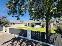 Charming single-story home with a well-manicured lawn, secure fence, and mature trees at 2450 E Clarendon Ave, Phoenix, AZ 85016