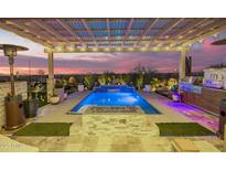 Inviting pool area featuring an outdoor kitchen, fire pit, pergola, and serene water feature for ultimate relaxation at 26716 W Ponderosa Ln, Buckeye, AZ 85396