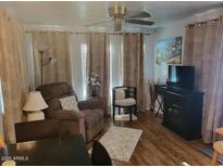 Cozy living room featuring a ceiling fan, recliner, and soft, neutral-toned curtains at 306 S Recker Rd # 212, Mesa, AZ 85206