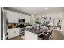 Modern kitchen featuring white cabinets, granite countertops, stainless steel appliances, and an island with seating at 4521 W Kirkland Ave, San Tan Valley, AZ 85144