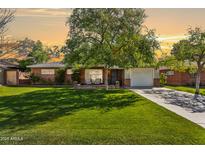 Charming single-story brick home with lush green lawn and mature tree, featuring a cozy front porch at 5529 N 19Th St, Phoenix, AZ 85016