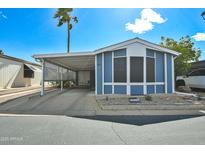 Charming blue home with a carport, manicured landscaping, and a sunny sky at 5735 E Mcdowell Rd # 197, Mesa, AZ 85215