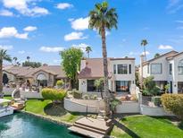 Waterfront home with private dock and lush landscaping along the water's edge and desert surroundings at 10365 N 101St Pl, Scottsdale, AZ 85258