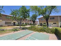 View of tan condos with a shuffleboard and green space in a tidy community at 5429 N Black Cyn Hwy, Phoenix, AZ 85015