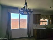 Eat-in kitchen featuring a modern chandelier, window with patterned curtain, and stainless steel sink at 9302 W Georgia Ave, Glendale, AZ 85305