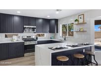 This is a kitchen with a quartz countertop island, stainless steel appliances, and black cabinets at 1012 E Rosebud Dr, San Tan Valley, AZ 85143