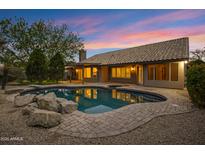 Inviting backyard pool with rock features and brick surround under a colorful dusk sky at 3060 W Ironwood Cir, Chandler, AZ 85226