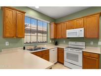 Bright kitchen features oak cabinets, a double basin sink beneath a window, and modern appliances at 3708 W Rushmore Dr, Anthem, AZ 85086