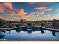 Backyard pool featuring tiered waterfall and stunning sunset views, perfect for relaxing evenings at 41006 N Noble Hawk Way, Anthem, AZ 85086