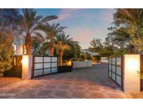 Elegant driveway with brick pavers and palm trees leading to a modern home at dusk at 6216 N 38Th Pl, Paradise Valley, AZ 85253