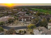 Stunning aerial view of a luxury home with a tile roof, lush landscaping, and a golf course nearby at sunset at 9280 E Thompson Peak Pkwy # 29, Scottsdale, AZ 85255