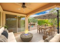Relaxing back patio with a fire pit, dining area, and comfortable seating, perfect for outdoor entertaining at 12957 W Hummingbird Ter, Peoria, AZ 85383