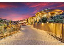 Exterior view of gated Mediterranean-style home on landscaped lot at dusk at 14360 E Desert Cove Ave, Scottsdale, AZ 85259