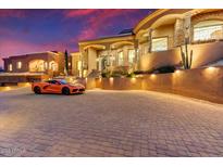 Mediterranean-style home at sunset featuring a paved circular driveway and a sports car at 14360 E Desert Cove Ave, Scottsdale, AZ 85259