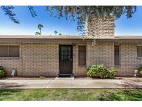 Exterior shot of home's front door and brick facade, framed by landscaped greenery and the hint of mature shade trees at 2015 E Southern Ave # 2, Tempe, AZ 85282