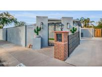 Charming gated front entrance featuring decorative ironwork, desert landscaping and walkway to front door at 2202 E Lincoln Dr, Phoenix, AZ 85016