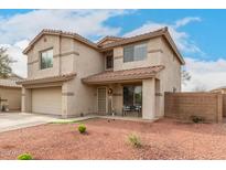 Two-story home with front porch, two-car garage, and desert-style landscaping at 13153 W Clarendon Ave, Litchfield Park, AZ 85340