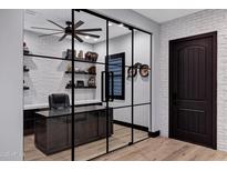 Modern office with glass wall, wood floors, and a built-in desk with shelving at 20745 N Verbena Ln, Maricopa, AZ 85138