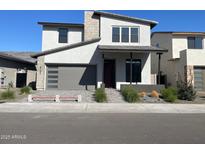 Modern two-story home featuring a gray garage door, covered front porch, and professionally landscaped front yard at 6735 N 9Th Dr, Phoenix, AZ 85013