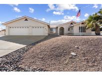 Charming single-story home featuring a well-manicured xeriscaped yard, three-car garage and an American flag at 825 N Sierra Vista Dr, Wickenburg, AZ 85390