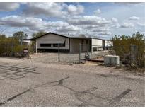 Charming single-story home featuring desert landscaping, fenced yard, and white siding under a cloudy sky at 10997 N Hualapai Dr, Casa Grande, AZ 85122