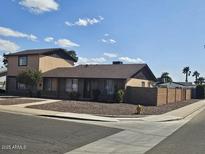 Tan two-story home with a gravel yard and desert landscaping plus a tall brick fence along the perimeter at 2255 W Bloomfield Rd, Phoenix, AZ 85029