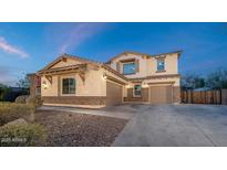 A warm two-story home features a three car garage and stone accents under a beautiful sky at 13346 W Jesse Red Dr, Peoria, AZ 85383