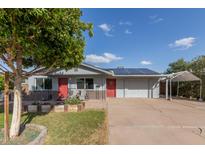 Charming single-story home featuring a red door, solar panels, and a covered parking area at 3027 S Clementine Dr, Tempe, AZ 85282