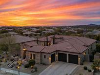 Stunning home boasts a tile roof, stone accents, three-car garage, and meticulously landscaped grounds under a breathtaking sunset at 32754 N 15Th Gln, Phoenix, AZ 85085