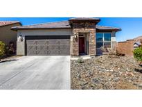 Charming single-story home featuring a stone facade, a two-car garage, and low-maintenance desert landscaping at 8836 S 165Th Ave, Goodyear, AZ 85338