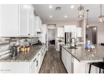 Spacious kitchen with white cabinets, stainless steel appliances, granite countertops, and tile backsplash at 9302 W White Feather Ln, Peoria, AZ 85383