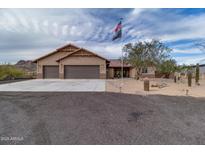 Beautiful tan home boasts a three-car garage, flag pole and lovely desert landscaping at 156 E Frontier St, Apache Junction, AZ 85119