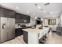 Modern kitchen features dark cabinets, granite counters, stainless steel appliances, and island with bar stool seating at 1756 E Bridgeport Pkwy, Gilbert, AZ 85295