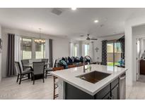 This kitchen features stainless appliances, gray cabinets, white countertops and an island with seating facing the dining area at 5383 N 205Th Dr, Buckeye, AZ 85396