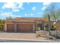 Charming single-story home with a tile roof, stone accents, three-car garage and desert landscaping at 7915 E Stonecliff Cir, Mesa, AZ 85207